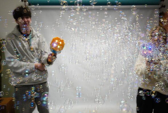 Two photography students play with bubble machines to show the advantages of us using different settings