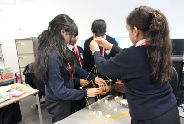 Local schoolgirls building a tower out of spaghetti and marshmallows in the Mace workshop. 