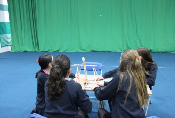 Four school girls see how far their catapult can fire a tiddlywink.